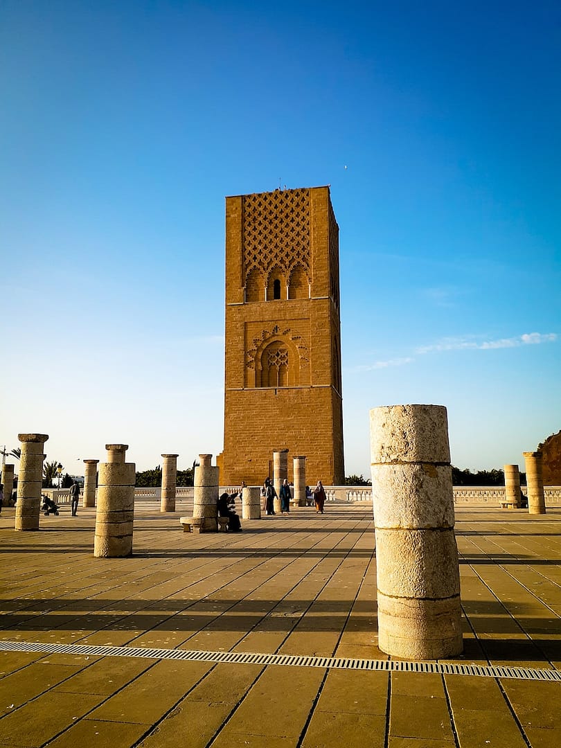 a large stone tower with Hassan Tower in the background